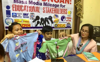 <p><strong>ECO BAGS.</strong> School teacher Aeia Katrina A. Valenciano (left), with her student Maurice Kim Camillon and Maribel Pascua, principal of Macayepyep Elementary School in Ilocos Norte, show the finished eco-bag products. Valenciano said aside being eco-riendly, the 'green bags' are durable enough to last for years. <em>(Photo by Cherry Joy D. Garma)</em></p>