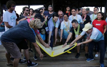 <p><strong>SURFING</strong>.  PSC Commissioner Ramon Fernandez (4th from right) leads the ceremonial breaking of a surfboard to kick off the 25th Siargao International Surfing Cup in Cloud 9, General Luna town on Saturday (Oct. 5, 2019).  Fernandez was joined by Surigao del Norte Governor Francisco Matugas (1st from right), Rep. Bingo Matugas (2nd from right), General Luna Mayor Cecilia Rusillon (3rd from right), Tourism Director Joseph Fernando Ortega (5th from right), and 2018 surfing cup champion Skip McCullough (1st from left). <em>(PNA photo by Alexander D. Lopez)</em></p>