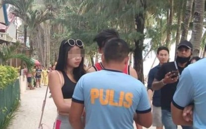 <p><strong>APPREHENDED.</strong> The Malay municipal police on Thursday (Oct. 10, 2019) fined the Taiwanese tourist (in shorts) PHP2,500 for “display of erotic and lewd picture”, for wearing a two-piece string bikini at a beach on Boracay Island. Officials of the Boracay Inter-Agency Management and Rehabilitation Group and the police urged tourists on the island to respect Philippine culture and tradition. <em>(Photo courtesy of Tristan Gelito Padilla)</em></p>