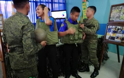 <p><strong>'NO' TO NPA RECRUITMENT.</strong> Students of the University of Antique try on military gear during Friday’s (Oct. 11, 2019) celebration of the Local Government Code Month in Antique. The Philippine Army warned students not to get recruited by the New People’s Army. <em>(PNA photo by Annabel Consuelo J. Petinglay)</em></p>