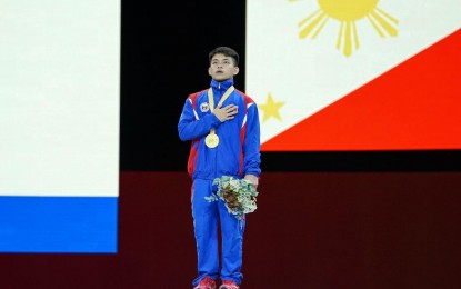 <p><strong>1ST FILIPINO WORLD CHAMPION.</strong>  World floor exercise champion Carlos Edriel Yulo proudly stands with right hand on his left breast while the Philippine anthem is played during the awarding ceremonies at the 49th FIG Artistic Gymnastics World Championships at the Hans Schleyer Halle in Stuttgart, Germany Saturday (Oct. 12, 2019).  Yulo also booked a ticket to the 2020 Tokyo Olympic Games. <em>(Photo courtesy of Janet Tenorio)</em></p>