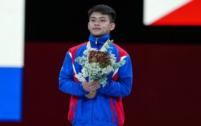 <p><strong>HAILED.</strong> Carlos Edriel Yulo proudly poses on the podium after clinching the men’s floor exercise gold medal at the 49th FIG Artistic Gymnastics World Championships at the Hans Schleyer Halle in Stuttgart, Germany last Saturday (Oct. 12, 2019). Communications Secretary Martin Andanar hailed Yulo for winning the country’s first-ever gold medal in the tournament. <em>(Photo courtesy of Janet Tenorio)</em></p>