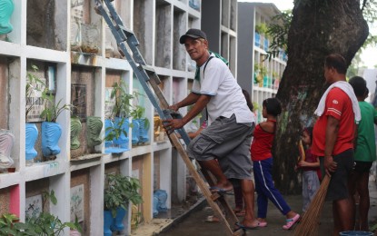 <p><strong>CONTENT IN SERVITUDE.</strong> 54-year-old Ricardo Silvestre prepares to clean a tomb at the Laloma Catholic Cemetery. At night, he also works as an anti-crime Officer in Payatas, Quezon City.<em> (PNA photo by Christine Cudis)</em></p>