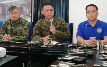<p><strong>SEIZED FIREARMS.</strong> Capt. Cenon Pancito III (center), public affairs chief of the Philippine Army’s 3rd Infantry Division, presents the firearms, ammunition, and explosives seized from the offices of progressive groups in raids conducted on Thursday (Oct. 31, 2019), during a press conference held at the Negros Occidental Police headquarters in Bacolod City on Friday afternoon (Nov. 1, 2019). With him are Col. Romeo Baleros (left), police provincial director; and Col. Benliner Capili, director of the Criminal Investigation and Detection Group 6 (Western Visayas). <em>(PNA photo by Nanette L. Guadalquiver)</em></p>