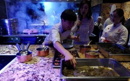 <p><strong>KOREAN CUISINE</strong>. Chef Jang Jinmo (left) shows event host Sam Oh how he would use leaves to decorate the main course. "A Taste of Korea's Finest" was held in BGC, Taguig City, last October 30, 2019. (<em>PNA photo by Cristina Arayata</em>) </p>