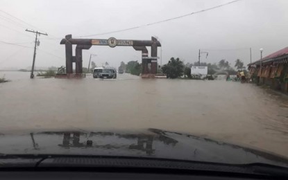 <p>Vehicles make their way through the flooded welcome arch of Apayao province in Luna, Apayao. <em>(Contributed photo)</em></p>
