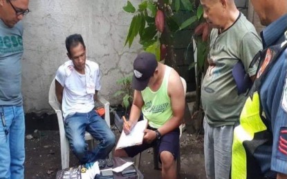 <p><strong>INVENTORY.</strong> Suspect Hector Pabon (seated, left) is being questioned by the police during the conduct of inventory following his arrest in a police buy-bust operation in Barangay Mambulac in Silay City, Negros Occidental on Sunday (Nov. 10, 2019). Pabon yielded over PHP300,000 worth of suspected shabu. <em>(Photo courtesy of Silay City Police Station)</em></p>