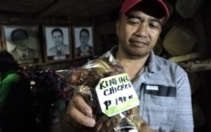 <p><strong>ALTERNATIVE TO PORK</strong>. The smoked-chicken, locally known as kini-ing, is selling like hotcake at the booth of the municipality of Bakun at the Agri-tourism fair in Wangal, La Trinidad, Benguet during the province's celebration of its 119th founding anniversary. The photo shows Bakun councilor Edgar Ognaden showing the pack of "kini-ing" chicken sold at PHP190 a pack. <em>(PNA photo by Liza T. Agoot)</em></p>
