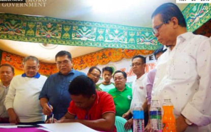 <p><strong>FOREST GUARDIANS</strong>. Bangsamoro Autonomous Region in Muslim Mindanao (BARMM) Chief Minister Ahod B. Ebrahim (right) looks on as a former rebel affixes his signature to help in the campaign to protect the region's forests on Saturday (Nov. 23, 2019). Some 400 former members of the Moro Islamic Liberation Front - Bangsamoro Islamic Armed Forces were hired as "palaws" or forest guards by the BARMM to protect its total 301,894 hectares of forest cover. <em>(Photo courtesy of BARMM Chief Minister’s Office)</em></p>