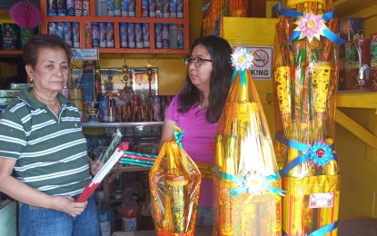 <p><strong>FIREWORKS SALES.</strong> Justina Gabuyo (left), director of the Philippine Pyrotechnics Manufacturers and Dealers Association Inc. and proprietor of the Global Fireworks and Trading in Bocaue, Bulacan holds a victory light luces, one of their best-selling firework items. She said that prices of firework products are lower this year compared to the previous years.<em> (Photo by Manny Balbin)</em></p>