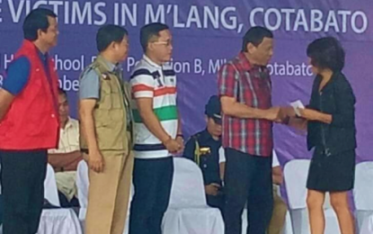 <p><strong>ASSISTANCE.</strong> President Rodrigo Duterte hands over financial assistance to a quake victim during a visit to M’lang, North Cotabato on Monday (Dec. 30, 2019). Aside from M’lang, other quake victims from the quake-hit towns Tulunan, Makilala, and Kidapawan City also received aid from the President. <em>(Screengrab from PCOO - RTVM)</em></p>