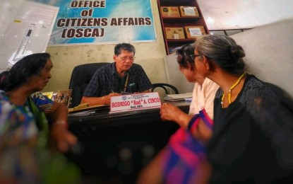 <p><strong>ELDER DISCOUNTS</strong>. Rodrigo Cinco, head of Office of Senior Citizens Affairs Tacloban, issues identification cards and booklets to senior citizens. OSCA is reminding the business sector here to grant senior citizens the appropriate discounts in goods and services listed under the law. <em>(Photo courtesy of OSCA Tacloban)</em></p>
