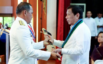 <p><strong>NEW AFP CHIEF</strong>. President Rodrigo Roa Duterte (right) hands over the Armed Forces of the Philippines (AFP) Command Saber to newly-installed AFP Chief of Staff Lieutenant General Felimon Santos during the AFP Change of Command ceremony at Camp General Emilio Aguinaldo in Quezon City on Jan. 4. (<em>Rey Baniquet/Presidential Photo</em>)</p>
