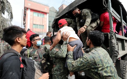 <p><strong>EVACUATION OPS.</strong> Police and military personnel carry a boy onto a truck during evacuation operations in Batangas on Monday (Jan. 13, 2020) morning. Residents are advised to take shelter in safer grounds as Taal Volcano's alert level is raised to Alert Level 4 which means “hazardous eruption is possible within days.” <em>(PNA photo by Joey Razon)</em></p>