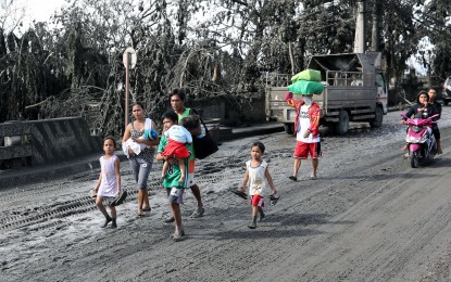 <p><strong>TO SAFER GROUNDS.</strong> A family walks barefoot along a muddy road towards the direction of Tanauan City from Talisay town in Batangas to seek safer grounds on Monday (Jan. 13, 2020). Some residents in areas affected by Taal Volcano's eruption on Sunday evacuated on their own, fearing for their safety as authorities raised the alert level 4, which means “hazardous eruption is possible within days". <em>(PNA photo by Joey O. Razon)</em></p>