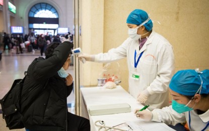 <p><strong>PUBLIC TRANSPORT SUSPENDED</strong>. A medical worker takes a passenger's body temperature at Hankou Railway Station in Wuhan, capital of central China's Hubei Province, on Jan. 22, 2020. Wuhan suspended public transportation, outward flights, and trains due to the outbreak of novel coronavirus. <em>(Photo courtesy of Xinhua/Xiao Yijiu)</em></p>