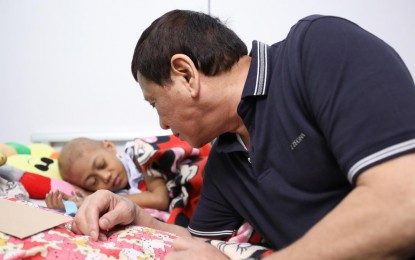 <p><strong>HOSPITAL VISIT. </strong> President Rodrigo R. Duterte checks on a sleeping pediatric cancer patient during his visit to the Southern Philippines Medical Center's Cancer Institute Children's Unit in Davao City on Dec. 23, 2018. Duterte on Thursday (Feb. 6, 2020) dared newly-appointed government officials to visit hospitals and see the sorry-state of patients there. <em>(Presidential photo by Toto Lozano)</em></p>