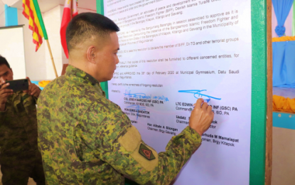 <p><strong>PERSONA NON-GRATA.</strong> Village officials of Datu Saudi Ampatuan, Maguindanao declare the Islamic State-linked Bangsamoro Islamic Freedom Fighters and Dawlah Islamiya terrorist group 'persona non grata' during a peace and development gathering initiated by the Army on Sunday (Feb. 9, 2020). Lt. Colonel Edwin Alburo (back at photo), commander of the Army's 57th Infantry Battalion, affixes his signature on the local officials’ declaration against violent extremism. <em>(Photo courtesy of 57IB)</em></p>