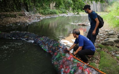 <p><strong>MANILA BAY REHAB</strong>. RCDS PP Popoy Robles is shown helping deploy the trash trap made of fishing net fashioned into a tube with recycled PET bottles, plastic containers with caps that function as floaters. A symbolic case of “trash trapping trash”.<em> (Photo courtesy of DMCI Homes)</em></p>