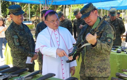 <p><strong>BISHOP FOR PEACE.</strong> Diocese of Calbayog Bishop Isabelo Abarquez (center), Lt. Gen. Gilbert Gapay, Philippine Army commanding general (right), and Philippine Army 8th Infantry Division commander Maj. Gen. Pio Diñoso III check firearms recovered by soldiers before the demilitarization ceremony in Camp General Vicente Lukban on Wednesday (Feb. 26, 2020). Diñoso has expressed optimism to attain peace in conflict-stricken Samar province after the three Roman Catholic bishops in Samar Island accepted the challenge to lead the localized peace talks with the New People’s Army. <em>(Photo courtesy of Philippine Army)</em></p>