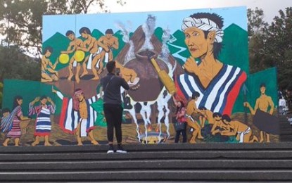 <p><strong>GHOST TOWN</strong>. Passersby take a photo of the mural that was supposed to serve as the backdrop of the Ipitik Festival on March 28 until April 5 at the Rose Garden of the Burnham Park. The event was canceled due to the threat of the coronavirus disease 2019 (Covid-19). <em>(PNA photo by Pigeon Lobien)</em></p>