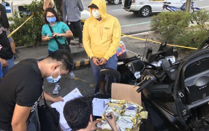 <p><strong>QUEZON CITY BUY-BUST.</strong> A police officer inspects the shabu seized from drug suspect Mark Anthony Gregorio Carlos (in yellow hoodie) during a buy-bust operation in Quezon City on Wednesday (March 11, 2020). The suspect yielded nine kilos of shabu worth PHP61.2 million. <em>(Photo courtesy of NCRPO)</em></p>
