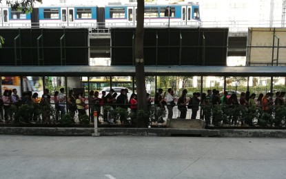 <p><strong>LONG QUEUES. </strong>Passengers line up at the Metro Rail Transit Line 3 (MRT-3) North Avenue Station (southbound) in Quezon City on Friday (March 13, 2020) while an MRT-3 train passes by just above them. The MRT-3 said the recent social distancing measure enforced on the rail service, which resulted in long queues and agitated passengers, was merely a simulation pending official guidelines<em>. (PNA photo by Aerol Pateña)</em></p>