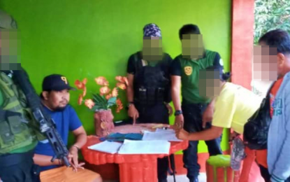 <p><strong>HANDCUFFED.</strong> Village councilor Michael Tamles (left, seated with cap) of Barangay Sucob, Columbio, Sultan Kudarat looks on while personnel of the Philippine Drug Enforcement Agency (PDEA)-Region 12 accounts the suspected shabu allegedly seized from him on Friday (March 13, 2020). The suspect is included in PDEA-12's top ten target-listed personalities in Sultan Kudarat province. <em>(Photo courtesy of PDEA-12)</em></p>