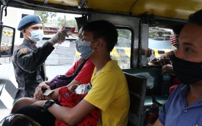 <p><strong>TEMPERATURE CHECK.</strong> A police personnel checks the temperature of passengers of a jeepney from Caloocan to Bulacan on Sunday (March 15, 2020). The measure is part of the one-month community quarantine implemented in Metro Manila starting Sunday to prevent the spread of the deadly coronavirus. <em>(PNA photo by Oliver Marquez)</em></p>