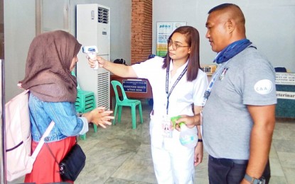 <p><strong>CLOSED BORDERS</strong>. A nurse checks the body temperature while a personnel of the Civil Aviation Authority of the Philippines sprays alcohol on the hand of a passenger bound for Jolo, Sulu on Monday (March 16, 2020) at the Zamboanga International Airport. Effective Monday midnight, land, air and sea travel is suspended as precautionary measure. <em>(Photo courtesy of Jerry Amaga)</em></p>