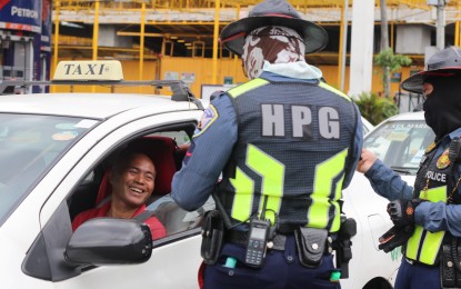 <p><strong>‘BE SAFE AT HOME’.</strong> Police officers tell a cab driver to follow the government order restricting public movement to contain the spread of Covid-19. They recorded the names of the drivers and told them to protect themselves and go home directly. <em>(PNA photo by Christine Cudis)</em></p>