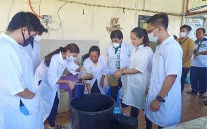 <p><strong>FROM MOLASSES TO ETHANOL</strong>. Mariano Marcos State University (MMSU) President Shirley C. Agrupis (3rd from right, foreground) on Wednesday (March 18, 2020) inspects the preparation of molasses by former students from the MMSU College of Medicine. Molasses are turned into ethanol through the process of fermentation.<em> (PNA photo by Reynaldo E. Andres)</em></p>