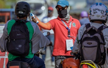 <p><strong>FACE MASK REQUIRED.</strong> A city government worker with mask checks the temperature of a motorist at a checkpoint in Tacloban City. Anyone who will stay outdoor is required to wear a face mask starting Saturday (March 21, 2020) as the city government enforces the 23-day lockdown to fight the spread of the coronavirus disease 2019. <em>(Photo courtesy of Rommel Cabrera)</em></p>
