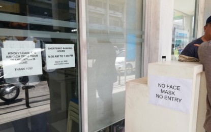 <p><strong>BANK ENTRY POLICY.</strong> A bank branch in Bacolod City posts notices of its adjusted banking hours and “no mask, no entry” policy which took effect on Monday (March 23, 2020). Mayor Evelio Leonardia said the city government supports such move of the Bankers’ Club of Negros Occidental amid the continued threat of the new coronavirus disease (Covid-19). <em>(PNA photo by Nanette L. Guadalquiver)</em></p>