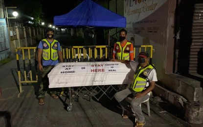 <p><strong>STERN WARNING</strong>. Two white coffins, one each at two checkpoints in the major entry points of Barangay Mulawin, Orani, Bataan, are displayed next to the village watchmen on duty. “Stay Home or Stay Here, Covid–19 is real”, says the warning written on the coffins. <em>(PNA photo by Ernie Esconde)</em></p>