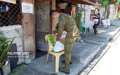 <p><strong>RELIEF OP.</strong> An Army trooper sets down relief goods outside a house in Barangay 175 in Camarin, Caloocan City on Thursday (March 26, 2020). Army troopers helped distribute relief goods provided by the private organizations “K-Noonas Buy Your Food” and “AvengersPH”. <em>(Photo courtesy of Army Chief Public Affairs Office)</em></p>