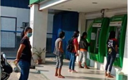 <p><strong>SOCIAL AMELIORATION.</strong> Pantawid Pamilyang Pilipino Program (4Ps) beneficiaries observe social distancing as they get their monthly allowance from a Landbank ATM. The DSWD along with its partner agencies vowed to provide cash assistance to low-income families affected by the month-long enhanced community quarantine in Luzon via the Social Amelioration program. <em>(Photo courtesy of DSWD)</em></p>