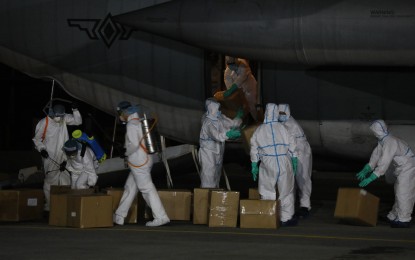 <p><strong>ARRIVAL OF PPE SETS</strong>. Philippine Air Force (PAF) personnel in hazmat suits unload tons of government-procured personal protective equipment (PPE) from a PAF C-130 cargo plane at the Villamor Airbase in Pasay City on Tuesday evening (March 31, 2020). The PPE sets are intended for front-liners in the fight against Covid-19. (<em>PNA photo by Avito C. Dalan</em>) </p>