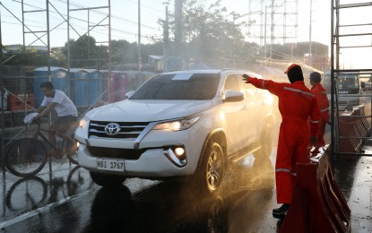 <p><strong>DISINFECTION.</strong> Motorists slow down as they pass a disinfection station set up by the Department of Public Works and Highways- National Capital Region (DPWH-NCR) along Marcos Highway to disinfect vehicles entering Metro Manila from Rizal province on April 2, 2020. This is part of the various government measures aimed at halting the spread of the coronavirus disease 2019 (Covid-19). <em>(PNA photo by Joey O. Razon)</em></p>