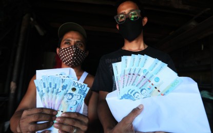 <p><strong>CASH AID</strong>. Residents of Barangay Vitalez in Parañaque City display the PHP8,000 cash they received as assistance from government on April 3, 2020. Some 18 million low-income households will receive the government subsidy during the enhanced community quarantine imposed to contain coronavirus disease. <em>(PNA photo by Avito C. Dalan)</em></p>