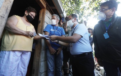 <p><strong>FINANCIAL ASSISTANCE</strong>. Presidential Peace Adviser Secretary Carlito Galvez, the chief implementer of the government's national policy on addressing the coronavirus disease 2019 (Covid-19) pandemic; and Parañaque City Mayor Edwin Olivarez (right), make house-to-house delivery of the PHP8,000 cash assistance from the government in Barangay Vitalez, Parañaque City on Friday (April 3, 2020). Some 18 million low-income households will receive the government subsidy at this time of the implementation of the enhanced community quarantine. <em>(PNA photo by Avito C. Dalan)</em></p>