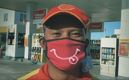 <p><strong>SMILE</strong>. A worker at a gasoline station dons a smiley-scribbled face mask. The masked employee is among those featured at a short video entitled “Smile”, a tribute to the front-liners braving the Covid-19 pandemic.<em> (Screenshot from "Smile" video)</em></p>