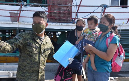<p><strong>UNDER QUARANTINE</strong>. A soldier assists the returning Filipino migrants upon arrival Monday (April 6, 2020) at the port of Zamboanga coming from Sibakil Island, Lantawan, Basilan, where they have undergone 21-day quarantine upon arrival on March 16 from Malaysia. All of the migrants were found negative of the 2019 coronavirus disease.<em> (Photo courtesy of WesMinCom PIO)</em></p>