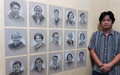 <p><strong>HEROES.</strong> Aurelio Castro III stands beside the portraits of the 15 physicians who succumbed to the coronavirus disease.  The portrait sketches are displayed on his online gallery. <em>(Photo courtesy of Aurelio Castro III) </em></p>