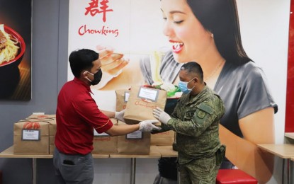 <p><strong>PARTNERSHIP AMID CRISIS</strong>. A staff from fast-food chain Chowking in Butuan City turns over lunch packs to Army personnel for distribution to front-liners at quarantine checkpoints in Butuan City. 402nd Infantry Brigade commander, Brig. Gen. Maurito L. Licudine thanked various business establishments for their all-out support to the front-liners.<em> (Photo courtesy of CMO, 402nd Infantry Brigade)</em></p>