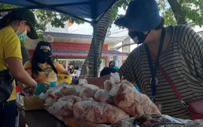 <p><strong>MOBILE MARKET</strong>. A customer checks on meat packs being sold by vendors in the Department of Agriculture-Region 10's "Kadiwa on Wheels." In Cagayan de Oro City alone, the mobile market has generated at least PHP1.9 million in sales since it began operation at the start of April 2020<em>. (Photo courtesy of DA-10)</em></p>