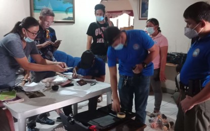 <p><strong>INVENTORY</strong>. Police operatives look over items confiscated during a search on a house allegedly used for cyber-pornography in Dumaguete City. A Norwegian national and his Filipino live-in partner were arrested during a search on Wednesday afternoon (April 29, 2020). <em>(Photo by Juancho Gallarde)</em></p>