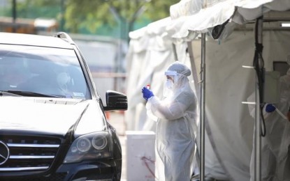 <p><strong>MORE TESTING OPTIONS.</strong> A health worker from the Taguig city government gets a swab sample from a motorist at a drive-thru testing center in Bonifacio Global City on Wednesday (April 29, 2020). Aside from drive-thru testing centers, those who do not have personal vehicles can avail of 'hatid sundo' service where they will be brought to a health center by an ambulance for testing. <em>(PNA file photo by Lloyd Caliwan)</em></p>