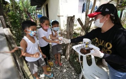 <p><strong>FEEDING PROGRAM.</strong> A staff member of the Davao de Oro mobile kitchen hands over nutritious meals to the children on Monday (May 4) as part of the Kusina ng Kalinga program of the province. The program aims to feed 14,000 children with nutritious foods to ease the impact of the 2019 coronavirus disease (Covid-19) crisis on families. <em>(Photo courtesy of Davao Oro PIO)</em></p>