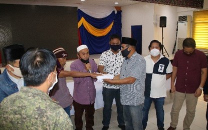 <p><strong>SETTLEMENT.</strong> Representatives of the Alulong and Bantuas clans in Bacolod-Kalawi, Lanao del Sur, sign a pact ending their blood feud Thursday, May 14. The settlement, presided by Bacolod-Kalawi municipal engineer Gorondatu Alulong, is witnessed by Col. Nolie Anquillano, the Army's 103rd Infantry Brigade deputy brigade commander, and local officials. <em>(Photo courtesy of the Army's 103rd Infantry Brigade)</em></p>